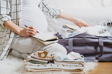 Pregnant woman packing hospital bag with checklist.