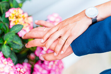 Romantic Close-Up of Couple's Hands with Wedding Rings Amid Vibrant Pink Blooms Symbolizing Love, Commitment, and Togetherness in a Beautiful Garden Setting