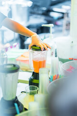 Close-Up of Gloved Hands Preparing Fresh Fruit Smoothie Using Blender in Kitchen Environment, Emphasizing Hygiene and Freshness in Beverage Preparation