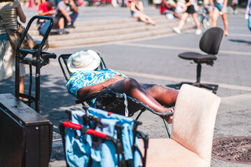 Man Relaxing in a Lounge Chair on a Sunny Day in a Busy Urban Park Scene Featuring People and Leisure Activities