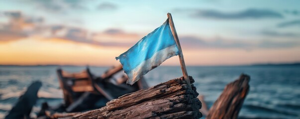 Flag waving above driftwood at sunset by the tranquil sea.