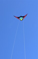 cometa multicolor volando al viento bajo un cielo azul despejado nitido luminoso