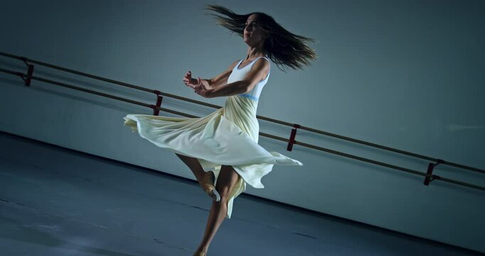 Super slow motion of graceful modern contemporary female dancer practices with focus and elegance in dance school or gym, refining her technique and expression through rigorous training and dedication