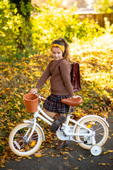 Obraz premium Little girl with a bicycle in the autumn forest. retro style clothes and bike