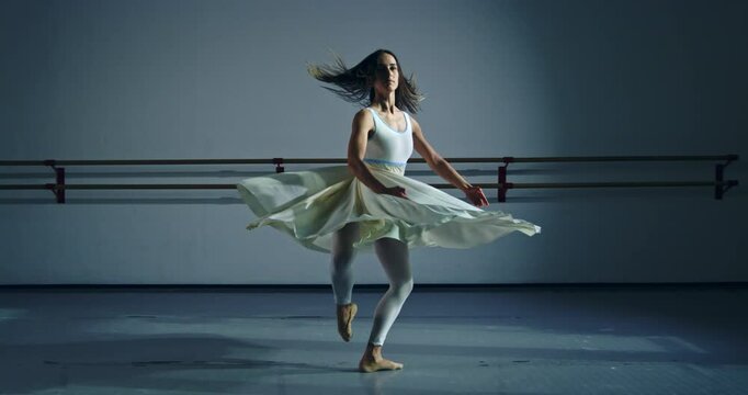 Super slow motion of graceful modern contemporary female dancer practices with focus and elegance in dance school or gym, refining her technique and expression through rigorous training and dedication