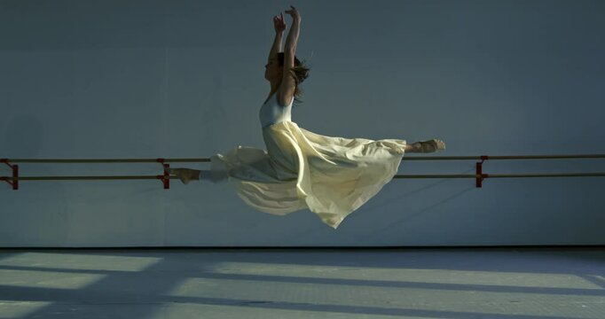 Super slow motion of graceful modern contemporary female dancer practices with focus and elegance in dance school or gym, refining her technique and expression through rigorous training and dedication