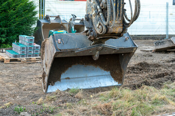 Closeup of an excavator bucket of an excavator doing earthwork. Earth is still sticking to the inner of the bucket.