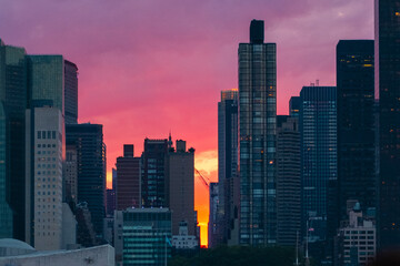 Obraz premium Spectacular Cityscape at Sunset with Illuminated Modern Skyscrapers Against a Vibrant Pink and Orange Sky Capturing the Beauty and Energy of Urban Life as Day Transitions into Night