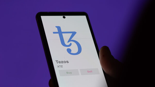 Close up on logo of XTZ tezos on the screen of an exchange. XTZ tezos price stocks, $XTZ on a device.
