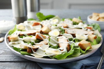Delicious Caesar salad with chicken on grey wooden table, closeup