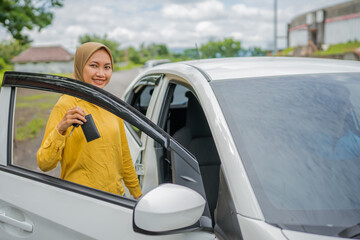 A cheerful and joyful woman stands next to her car, relishing a beautiful sunny day