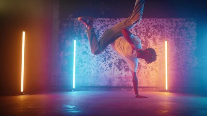 African American b-boy performing trick on floor in dance studio, slow motion. Breakdance and hip-hop, street style dances, young black man in casual clothes dancing alone, contemporary choreography