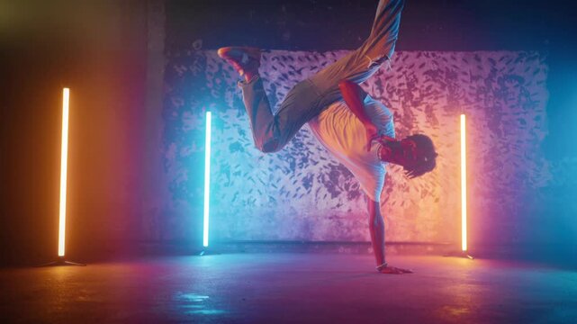 African American b-boy performing trick on floor in dance studio, slow motion. Breakdance and hip-hop, street style dances, young black man in casual clothes dancing alone, contemporary choreography