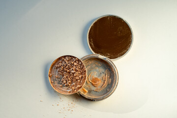 Broken palette with highlighter on a white table. Decorative cosmetics