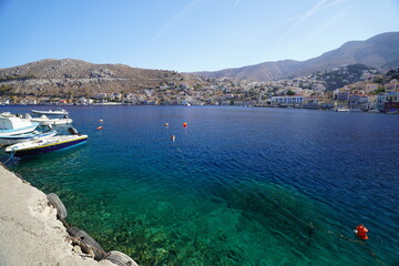 Naklejka premium boats in turquoise clear water on Symi island port