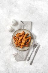 Baked chicken necks in a ceramic plate on a light culinary background top view