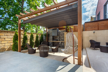 Backyard outdoor bbq zone with pergola, fireplace and hanging chair. Summer party place