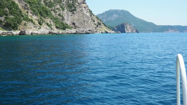 Calm waters stretch endlessly under a clear blue sky. Boat foreground showcases worn details while distant hills create tranquil backdrop. RT Dubovica Rocks near Kraljicina plaza and Canj, Montenegro.