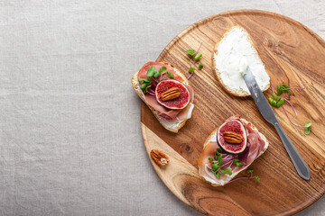 Slices of white bread with young cream cheese, prosciutto, freshly sliced figs and radish sprouts.
