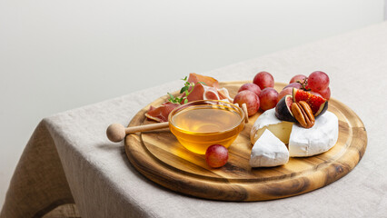 Charcuterie board with meat, cheese, grapes, nuts, honey and fresh figs.