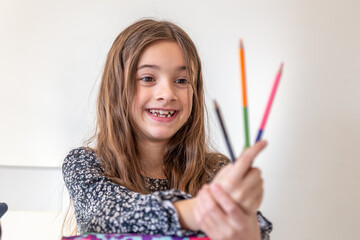 Happy girl is packing a backpack for school. The girl goes to school.