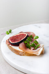 Bread with young cream cheese, meat, freshly sliced figs and radish sprouts.