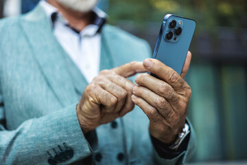 Phone, business and senior man in city, texting or internet browsing outdoors in urban street. Technology, cellphone and happy male ceo with 5g mobile smartphone for networking or social media.