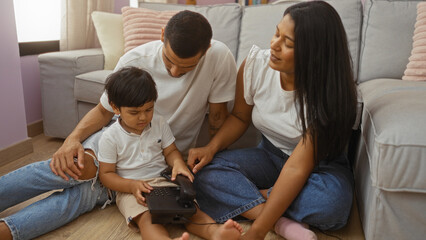 Latin family in a cozy living room, a woman and a man lovingly watch their young child using a telephone, significantly capturing the warmth and togetherness of home life.