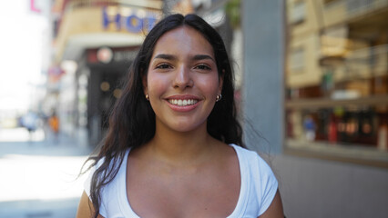 Young woman smiles on a bright day while walking in an urban city street, capturing the essence of a vibrant and lively town atmosphere, showcasing an attractive brunette enjoying the outdoors