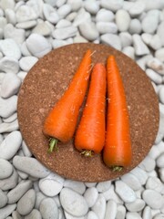 Fresh carrots on a brown paper on white stones