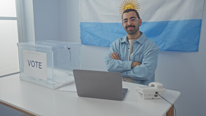 Young man with moustache standing in electoral college room with argentina flag, voting box, and...