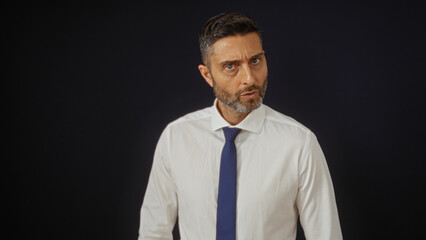 Handsome man posing in formal wear against a dark background, highlighting his stylish appearance and confident expression.