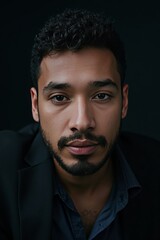 Fototapeta premium Portrait of a young man with a serious expression wearing a suit against a dark background 