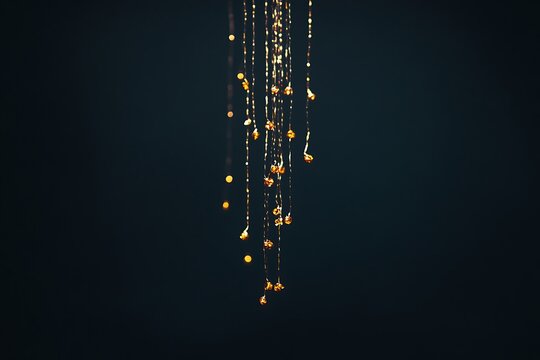 Golden droplets gracefully cascading on shimmering strings against a dark, elegant backdrop.