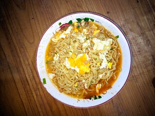 photo of instant noodle dish cooked with egg, served on a plate on the table