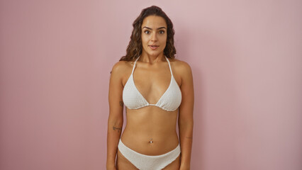 Fototapeta premium Young woman in a bikini standing over an isolated pink background, illustrating beauty, confidence, and a casual summer vibe