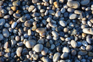 Gravel beach in Etretat, wet gravel texture, France, during winter season 