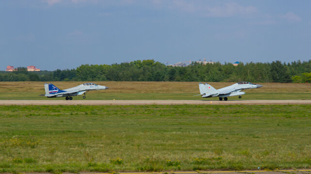 MAKS-2011 on territory of airfield LII im. Gromov. Russian MiG-29M2 multirole fighter jet with external fuel tanks and a MiG-35 (NATO-Fulcrum) fighter take off.  Zhukovsky, Russia - August 16, 2011