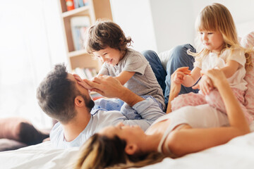 Obraz premium Happy family playing on bed with kids