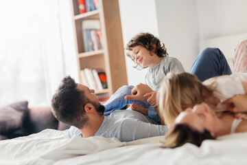 Happy family playing on bed with kids