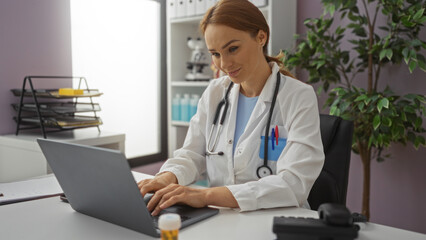 Female doctor working on a laptop in a modern clinic room, displaying professional focus while surrounded by medical equipment and interior decor.