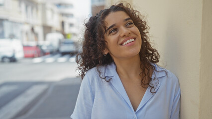 Young, beautiful, hispanic, woman smiling on an urban street on a sunny day.