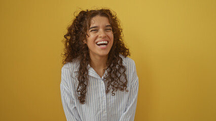 Young attractive hispanic woman smiling isolated over a yellow background wall wearing a striped light blouse