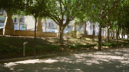 Obraz premium Blurred outdoor background featuring defocused trees and buildings on a sunny day with bokeh effects in a park setting