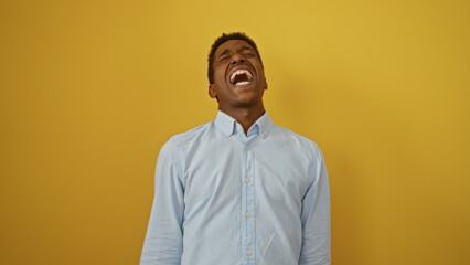 Obraz premium Handsome young african american man laughing joyfully against isolated yellow background conveying happiness and humor