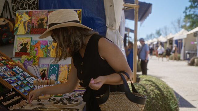 Woman browsing colorful artwork at outdoor market in palma mallorca spain on a sunny day