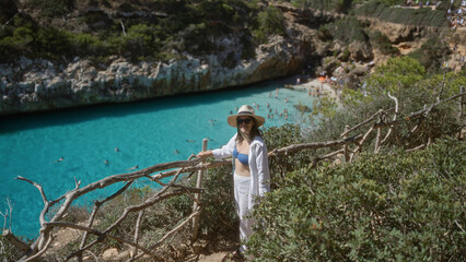 Young woman enjoying the scenic view of cala del moro in mallorca, spain, standing near clear...