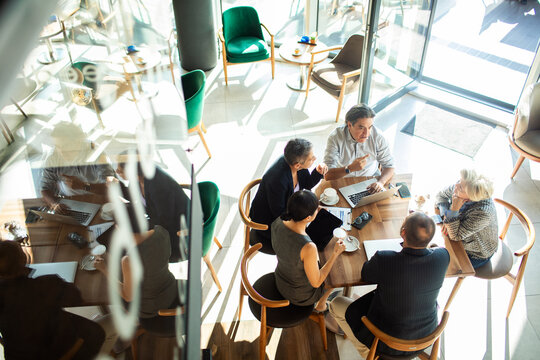 Group of business professionals smiling and discussing ideas over coffee in a cafe