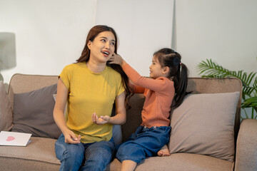 Lovely mom and little young daughter spending time together in their living room.