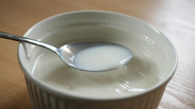 scooping milk with a spoon from a breakfast bowl full of milk